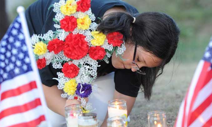 A woman presents flowers to victims near the movie theater where the shooting rampage happened in Aurora, Colorado, July 20, 2012. Photo: Xinhua