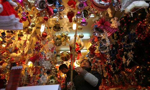 A shop clerk at Yuyuan Garden hangs up Christmas decorations Tuesday. Local shops have been busy preparing for the coming Christmas sales season. Photo: Cai Xianmin/GT