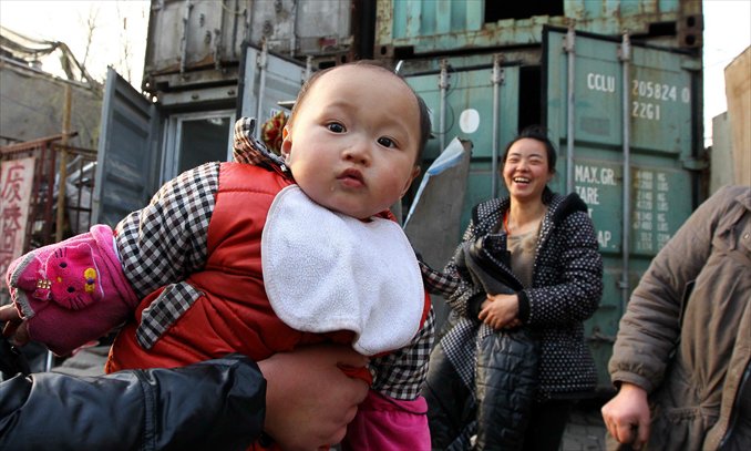 A baby investigates the camera with container homes in the background. Photo: Yang Hui/GT