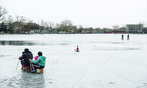 A family of three sleds on the ice despite being near a potentially dangerous melted area at Xihai Lake on Sunday. Photo: Li Hao/GT