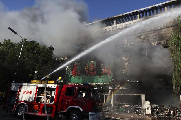 Firefighters spray water to put out a fire in Tianjin, North China, June 30, 2012. A fire broke out at a shopping mall in Tianjin's Jixian County on June 30. Photo: Xinhua