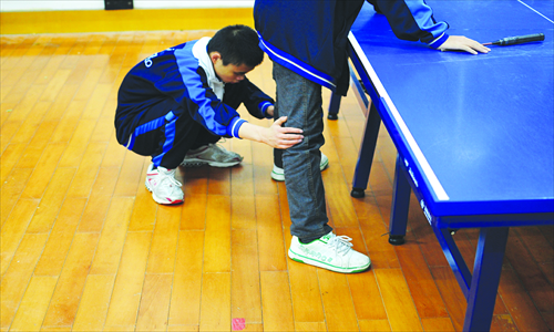 Liang touches his teammate's feet and tries to correct stance.