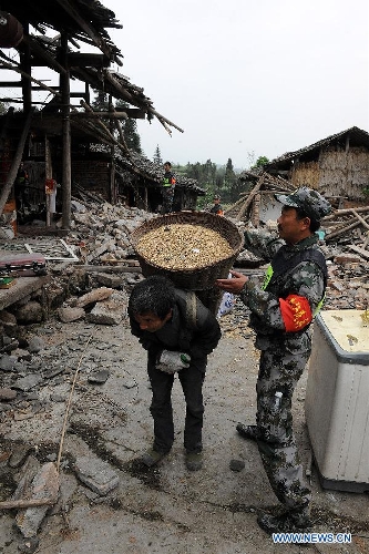 A militiaman and a villager help a 83-year-old villager (not seen in the picture) transfer her grain out of the ruins of her house at the quake-hit Lushan County, southwest China's Sichuan Province, April 21, 2013. A 7.0-magnitude earthquake jolted Lushan County on April 20, leaving at least 192 people dead and 23 missing. More than 11,000 people were injured. (Xinhua/He Junchang) 