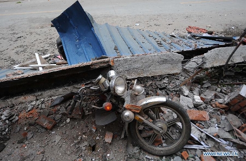A motorbike is crushed by a fallen object in Lingguan Town of Baoxing County in Ya'an City, southwest China's Sichuan Province, April 21, 2013. A 7.0-magnitude earthquake hit Lushan County of Sichuan Province on Saturday morning, leaving 26 people dead and 2,500 others injured, including 30 in critical condition, in neighboring Baoxing County, county chief Ma Jun said. (Xinhua/Xue Yubin) 