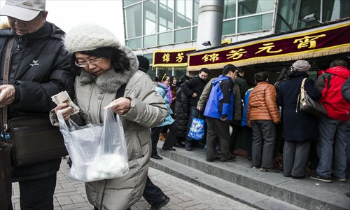 A couple inspects the yuanxiao they just bought from the stand at Ciqikou, Dongcheng district Monday. Other customers line up to buy the traditional Lantern Festival snack. Photo: Li Hao/GT