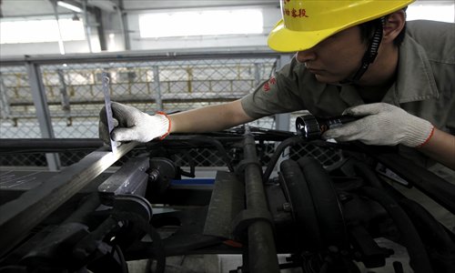 A technician measures the width of one of the sliding carbon strips on the top of a train. Photo: Yang Hui/GT