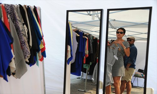 A lady tries on a dress at a local flea market. Photo: CFP