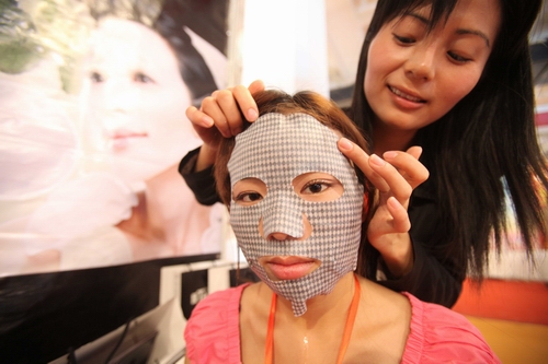 A woman tries on a facial mask with moisturizing and whitening functions at a beauty product exhibition at China International Exhibition Center, Chaoyang district on April 17, 2012. Photo: CFP