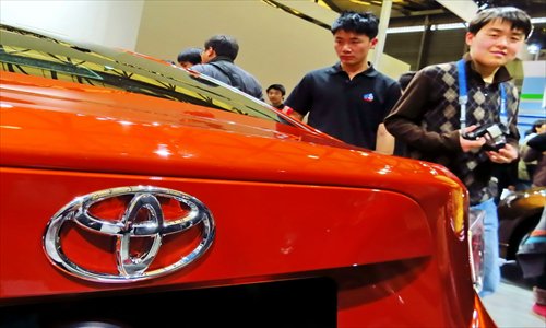 Visitors look at a car from Toyota at an automobile exhibition in Shanghai. Toyota sold around 76,900 cars in China during June, up 9 percent year-on-year, according to media reports Monday. Photo: CFP
