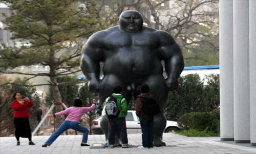 A student poses for a photo near a sculpture by Shen Hongbiao at Peking University. The sculpture was relocated last year. Photo: CFP