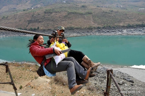 Residents from Shuangmidi Village cross the Nujiang River via a zip-line in Liuku County of Nujiang Lisu Autonomous Prefecture, southwest China's Yunnan Province, Feb. 2, 2013. More than 98 percent of Nujiang Lisu Autonomous Prefecture is occupied by mountains and valleys. The zip-lines have been quite popular transportation method along the Nujiang River since the ancient time. However, as transport conditions improve in recent years, a growing number of traditional zip-lines along the Nujiang River Valley have been dismantled or replaced by bridges. (Xinhua/Lin Yiguang)  