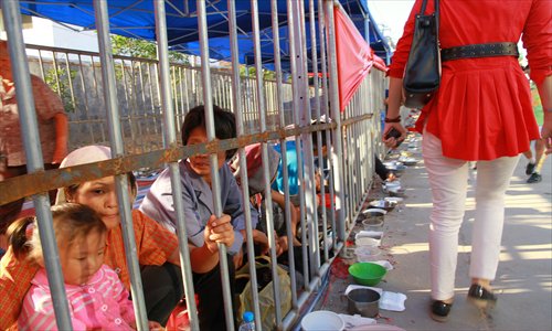 A visitor passes by beggars who are segregated behind bars at a Buddhist temple fair in Jiangxi Province. Photo: CFP