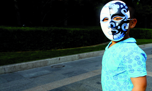 A mask-wearing child shows off a fake T-shirt. Photo: Guo Yingguang/GT