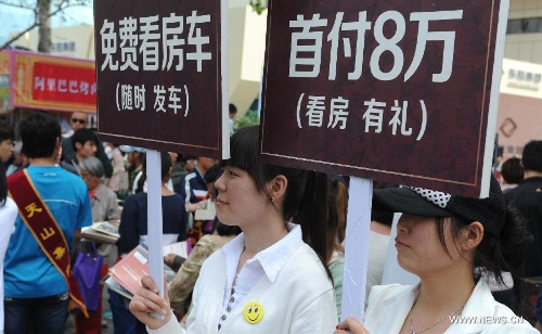 Salespersons hold posters to attract potential property buyers at Shijiazhuang Spring Housing Fair in Shijiazhuang, capital of north China's Hebei Province, April 29, 2013. The fair, which kicked off on April 29, will last for four days. (Xinhua/Wang Xiao)&nbsp; 