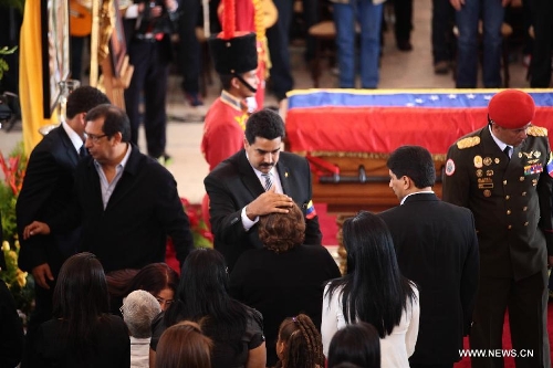 Elena Frias (C) receives condolences from Venezuela's President Nicolas Maduro (C L) in front of the body of late Venezuelan President Hugo Chavez during a honor ceremony at the Military Academy's fire chapell, prior to his carrying from the Military Academy to the Mountain Barracks, in the city of Caracas, capital of Venezuela, on March 15, 2013. Hundreds of thousands of Venezuelans Friday marched alongside the casket of their late President Hugo Chavez, as his remains were taken to the mountaintop barracks he once called home and today houses the Historic Military Museum. (Xinhua/AVN)