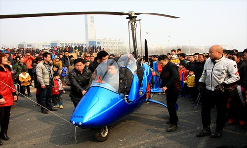 A young man displays a helicopter he constructed on his own at a temple fair in Luoyang, Henan Province on Sunday, attracting a large crowd of curious onlookers. This model is the third flying craft he has built for himself. Photo: CFP