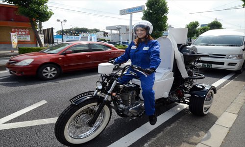 A female rider drives Toto's eco-friendly motorcycle Toilet Bike Neo, which uses biogas from discharges of livestocks or waste water, during a demonstration run for their domestic green campaign in Omiya, on Wednesday.  Photo: AFP