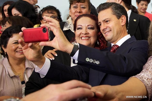 Image provided by Mexico's Presidency shows Mexican President Enrique Pena Nieto(R) taking photos during a celebration of the Teachers' Day at the Official Residence of Los Pinos in Mexico City, capital of Mexico, on May 15, 2013. (Xinhua/Mexico's Presidency)