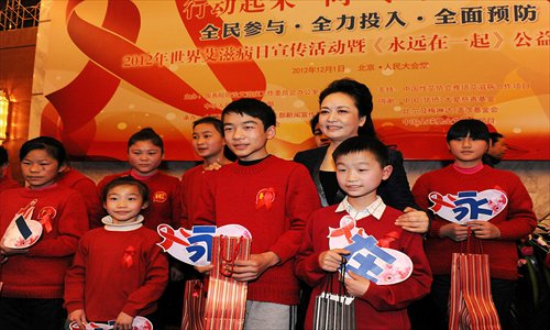 Peng Liyuan, a World Health Organization ambassador for the fight against AIDS and a publicity representative of the health ministry's AIDS control campaign, poses for pictures with teenagers participating in a charitable film on World AIDS Day. Photo: Xinhua