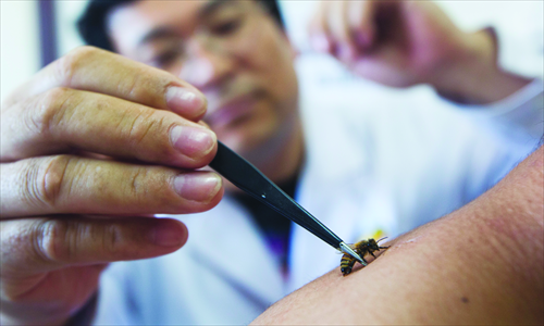 A doctor puts a bee on a patient with a pair of tweezers. Photo: IC