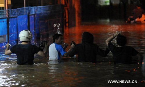 Residents wade their way home in the inundated street at Gudang Peluru complex, East Jakarta, January 16, 2013. Rainy season causing floods hit East Jakarta, on midnight Tuesday, forced 6000 people in East Jakarta area to be displaced by the overflowing Ciliwung river. (Xinhua/Veri Sanovri)  