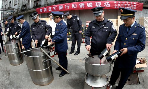 Officials destroy more than 3,000 bottles of knockoff wine Tuesday in Fengxian district. Police found the counterfeit wine, which was labeled as the well-known brand Lafite, at an unlicensed workshop last year. The case involved nearly 40 million yuan ($6.5 million). Photo: Xinhua 