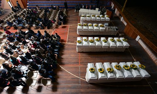 Relatives of victims sit in front of the coffins bearing the remains of those murdered by the Shining Path or the Peruvian Army during the counter-insurgent war (1980-2000), during a ceremony on Tuesday in Cuzco, Peru. Human rights organizations handed over to relatives the remains of 26 people, three of which belong to children, found in several common graves. Photo: AFP