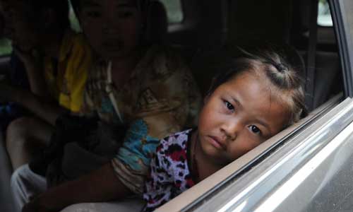 A girl to be displaced sits in a vehicle in Luozehe Town, Yiliang County, southwest China's Yunnan Province, Sept. 7, 2012.