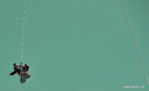 Residents from Shuangmidi Village cross the Nujiang River via a zip-line in Liuku County of Nujiang Lisu Autonomous Prefecture, southwest China's Yunnan Province, Feb. 2, 2013. More than 98 percent of Nujiang Lisu Autonomous Prefecture is occupied by mountains and valleys. The zip-lines have been quite popular transportation method along the Nujiang River since the ancient time. However, as transport conditions improve in recent years, a growing number of traditional zip-lines along the Nujiang River Valley have been dismantled or replaced by bridges. (Xinhua/Lin Yiguang)  