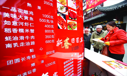 People look at a menu of ready-to-cook food that has been partially prepared by a restaurant for Spring Festival dinners in Shanghai Wednesday. Prices of ready-to-cook food for Spring Festival are up 5 to 8 percent from last year due to rising costs in raw materials, labor and rents. Photo: IC