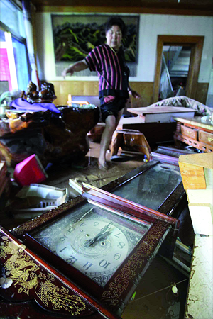 A woman attempts to clear up her devastated house in Beicheying village, Fangshan district Monday after the rainstorm. Photo: CFP