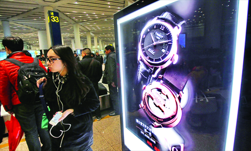 A woman passes by a luxury watch advertisement in Beijing Capital International Airport. Luxury product sales in China have been declining since last year, when the annual growth rate of the domestic luxury market dropped to around 7 percent from 30 percent in 2011, the Guangzhou-based Information Times newspaper reported Monday, citing a research report released by Bain & Co late last year. Photo: CFP