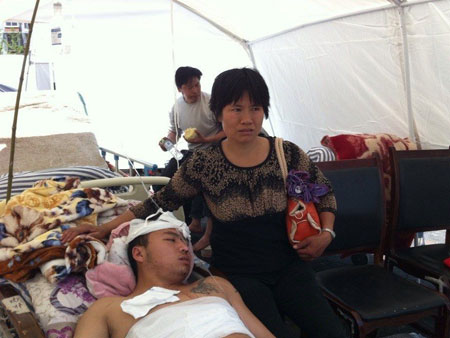 A mother who saved her son by moving away a slab weighing over 50 kilograms alone in the earthquake, looks after her son at a temporary treatment tent. Photo: West China City Daily