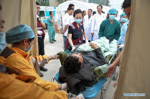 Health workers of Chongqing emergency medical service team wheel an injured person who was transported from the quake-hit Baoxing County to a tent in southwest China's Sichuan Province, April 21, 2013. al authorities. (Xinhua/Li Xin) 