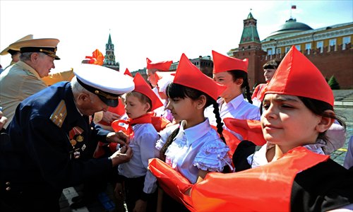 Veterans of the Soviet Army and Russian Communist Party tie red scarves around childrens' necks, symbolizing their initiation into the Young Pioneer Youth communist group created in the Soviet Union for children 10-14 years old, in Moscow's Red square on Sunday during the organization's celebration day. Some 3,000 pioneers took part in the ceremony. Photo: AFP