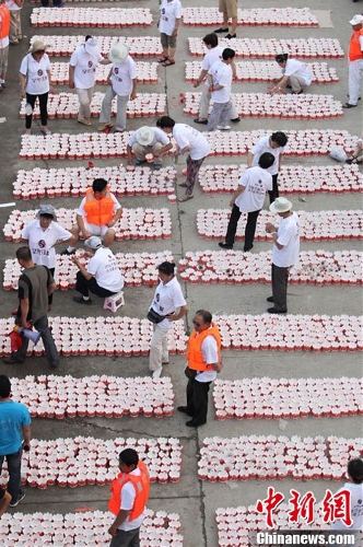 Volunteers prepare for the setting lantern activity. 300 people set 14630 river lanterns on the Songhua River in Ji Lin Province on July 7, 2013, creating a new Guinness World Record. (Photo: Xinhua/Chinanews.com)