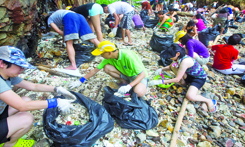 People clean up Big Wave Bay beach in Hong Kong on Sunday. Over 150 volunteers from the Hong Kong-based NGO Ecovision moved 217 full bags of plastic, plastic pellets and assorted marine trash off the beach after 150 tons of trash floated into the sea as a result of a recent typhoon. Photo: CFP
