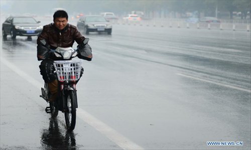 A man rides against rain on a road in Beijing, capital of China, November 3, 2012. The cold wave that has swept northwestern China is moving eastward and is expected to bring blizzards to parts of northern China, the National Meteorological Center (NMC) forecast on Saturday. Heavy snow will hit Inner Mongolia, Hebei, Shanxi and the mountainous areas in western Beijing, according to a posting on the NMC website. The NMC has issued a blue warning on blizzards for Saturday, the lowest level in disaster alarm after yellow, orange and red. Photo: Xinhua