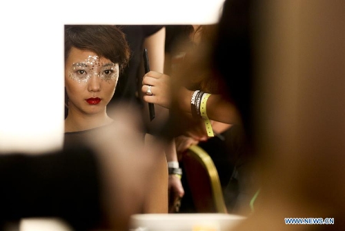 Chinese actress Wang Luodan gets her make-up done at the backstage before the presentation of Jenny Ji's fashion show during London Fashion Week in London, Britain, on Feb. 18, 2013. (Xinhua/Tang Shi)