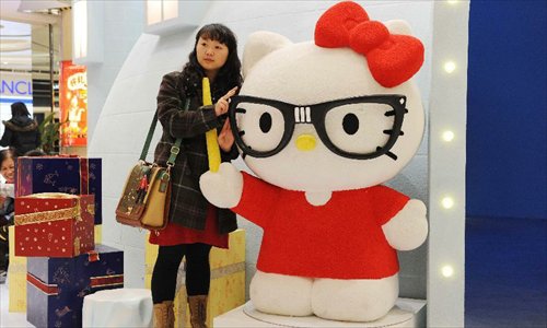 A woman poses for pictures with a red Hello Kitty in the Joy City in east China's Shanghai Municipality, Nov. 26, 2012. A big Hello Kitty exhibition themed on Hello Kitty's exploration in the polar regions would last from Nov. 24, 2012 to Feb. 24, 2013 in Shanghai. Photo: Xinhua