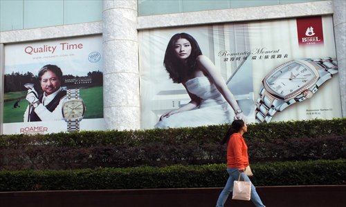 A woman walks past an advertisement for luxury watches in Yichang, Hubei Province, on October 17. According to a recent report by McKinsey & Co., the increasing consumption of luxury commodities will decrease in the future but is still higher than in any other country in the world. Photos: CFP