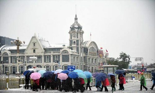 Tourists shelter from the sleet under umbrellas as as they walk near the Tian'anmen Square in Beijing, capital of China, on November 4, 2012. The capital city had witnessed snowfall and sleet since Saturday night as cold current swept north China and dropped temperature. Photo: Xinhua