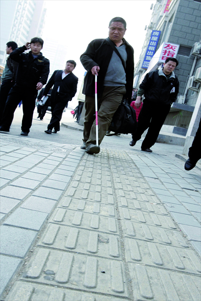 A man follows markings on the road in Beijing that are designed to help the visually impaired.  
