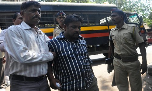 Indian builder Jamil Qureshi (center) is escorted by police in Thane on the outskirts of Mumbai on Sunday. Qureshi, one of two builders arrested over the deadly collapse of a seven-story apartment block that killed 74 people, appeared in court in western India. Photo: AFP