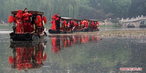 Newlyweds board on boats during a group wedding held in the Old Summer Palace, or Yuanmingyuan park, in Beijing, China, May 18, 2013. A total of 30 couples of newlyweds took part in event with traditional Chinese style here on Saturday. (Xinhua/Luo Xiaoguang)  