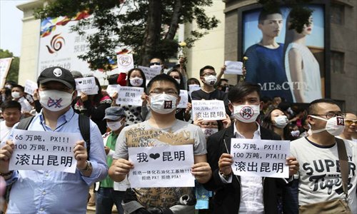 Residents of Kunming, the capital of Yunnan Province, wear masks and hold signs reading, 