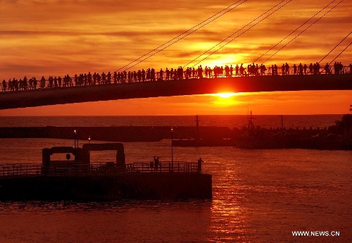 Visitors stand on a bridge to enjoy the scenery of sunset in Danshui, Xinbei, southeast China's Taiwan, July 3, 2013. Dubbed as the 