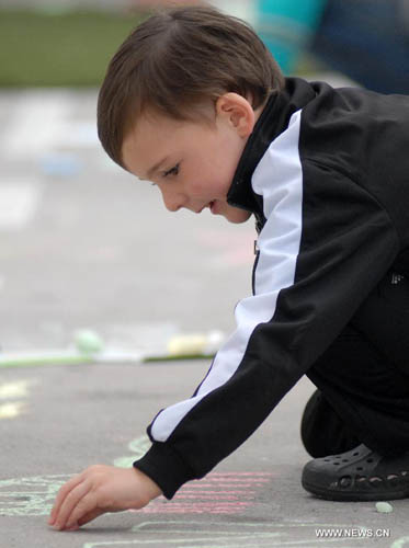 A child chalk-draws on the pavement during first Chalkupy Vancouver event in Vancouver, Canada, on September 22, 2012. People from all walks of life descend on Robson Street in downtown Vancouver at noon to create beautiful sidewalk chalk art together. Photo: Xinhua