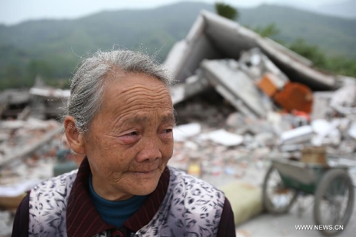 Gao Shizhen, a 75-year-old woman who lost her daughter-in-law during the earthquake, stands in front of her collapsed house at Longxing Village of Longmen Township in Lushan County, southwest China's Sichuan Province, April 21, 2013. A 7.0-magnitude earthquake hitting Lushan County Saturday morning has left 179 people dead till 9:25 Beijing Time (0125 GMT) on April 21, the China Earthquake Administration has announced. (Xinhua/Jin Liwang)  