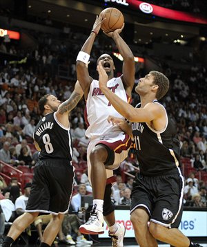 Miami Heat forward Chris Bosh (center) shoots between Brooklyn Nets Brook Lopez (right) and Deron Williams on Thursday. Photo: CFP